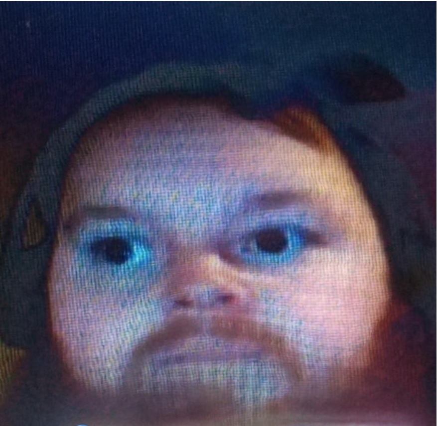 A photo of a computer screen showing an SnapChat filtered image of Jonathan appearing as a baby with a beard.